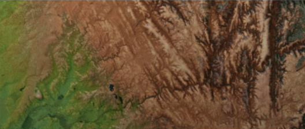Satellite imagery of farmland giving way to eroded mountain terrain.