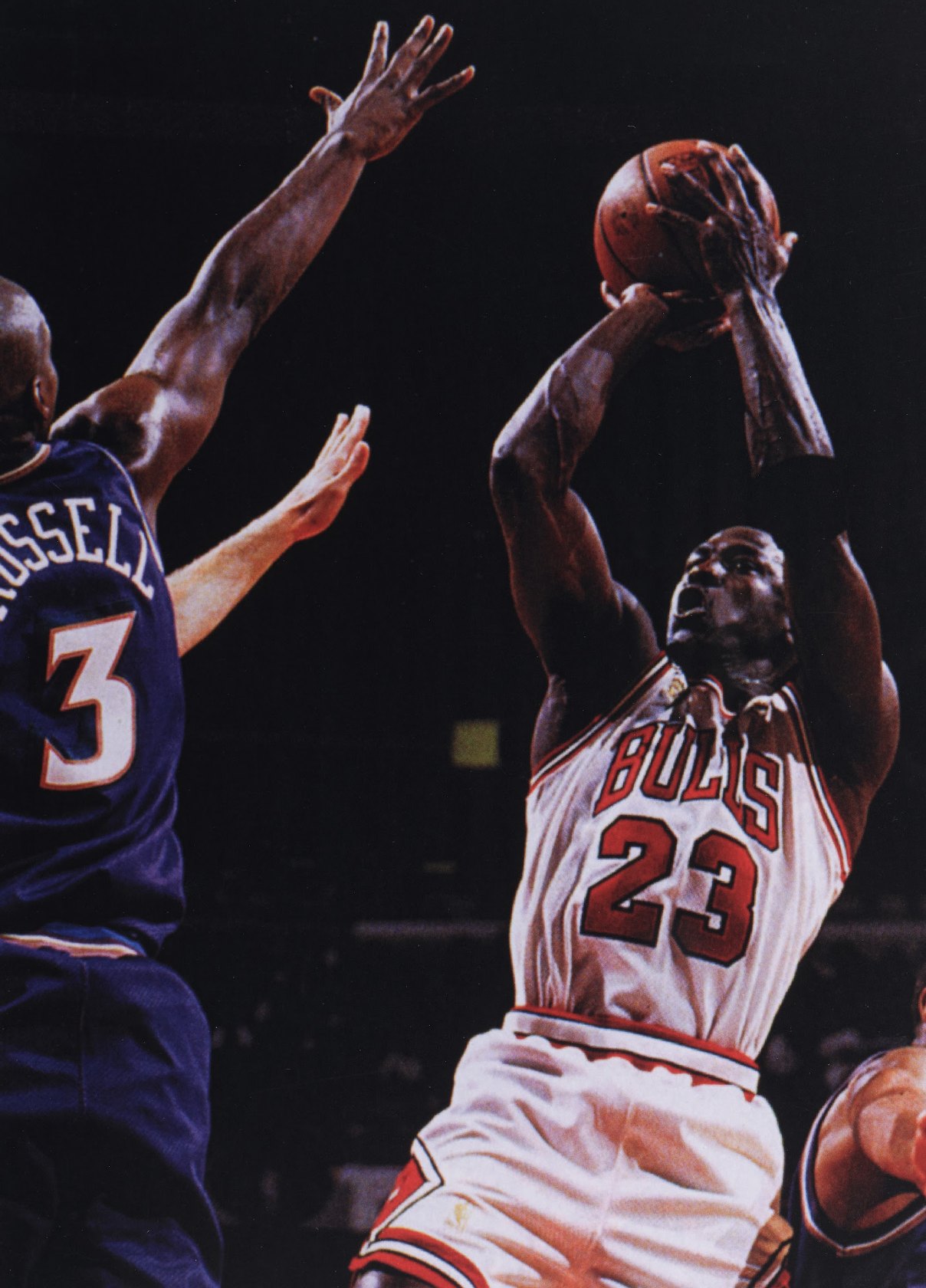 Michael Jordan in a white Bulls 23 jersey rising for a jump shot over a Jazz defender.