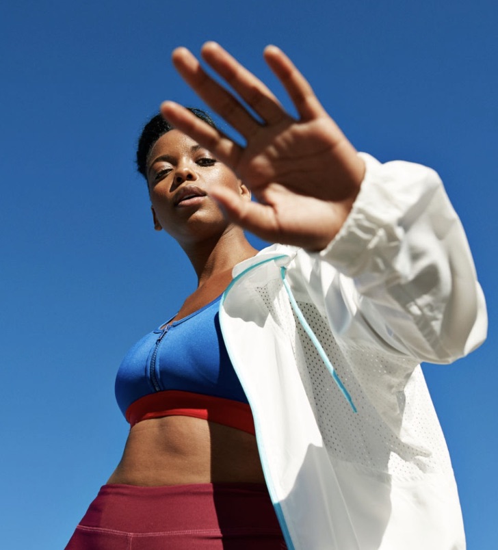 An athlete holds a hand up to the camera against a blue sky.